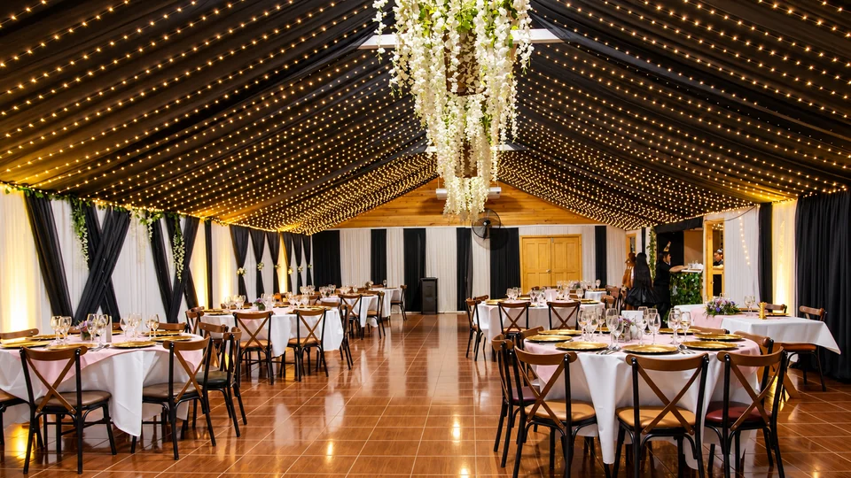 Salón principal preparado con mesas, sillas y un techo de luces cálidas